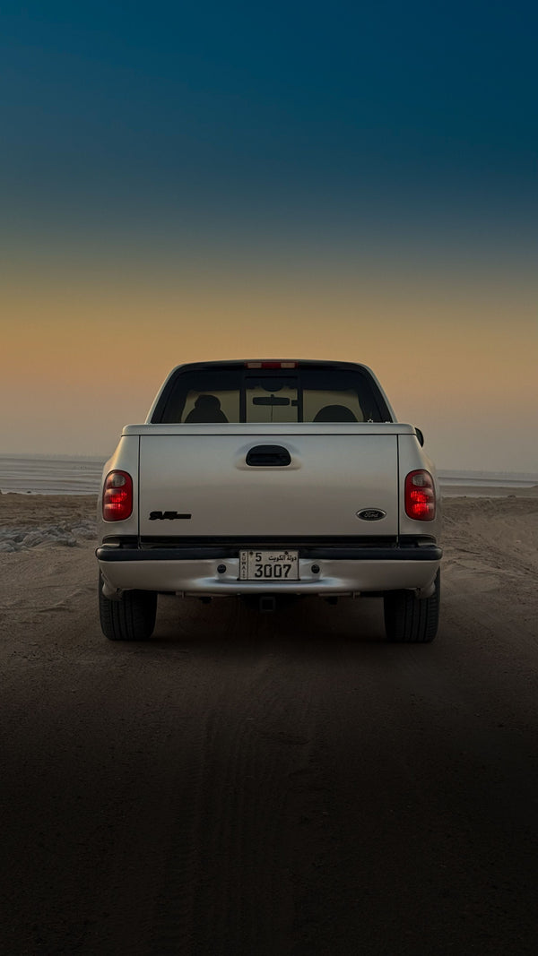 White pickup truck on a sandy road in Kuwait at sunset