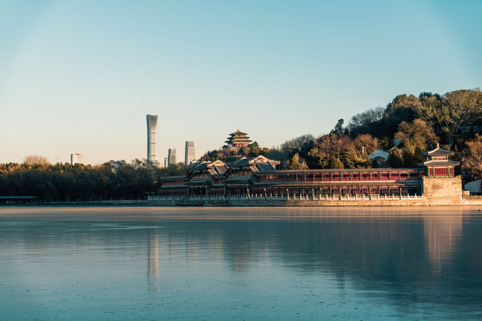 A tranquil view of Beihai Park with Beijing's skyline at dawn, capturing a blend of nature and architecture.