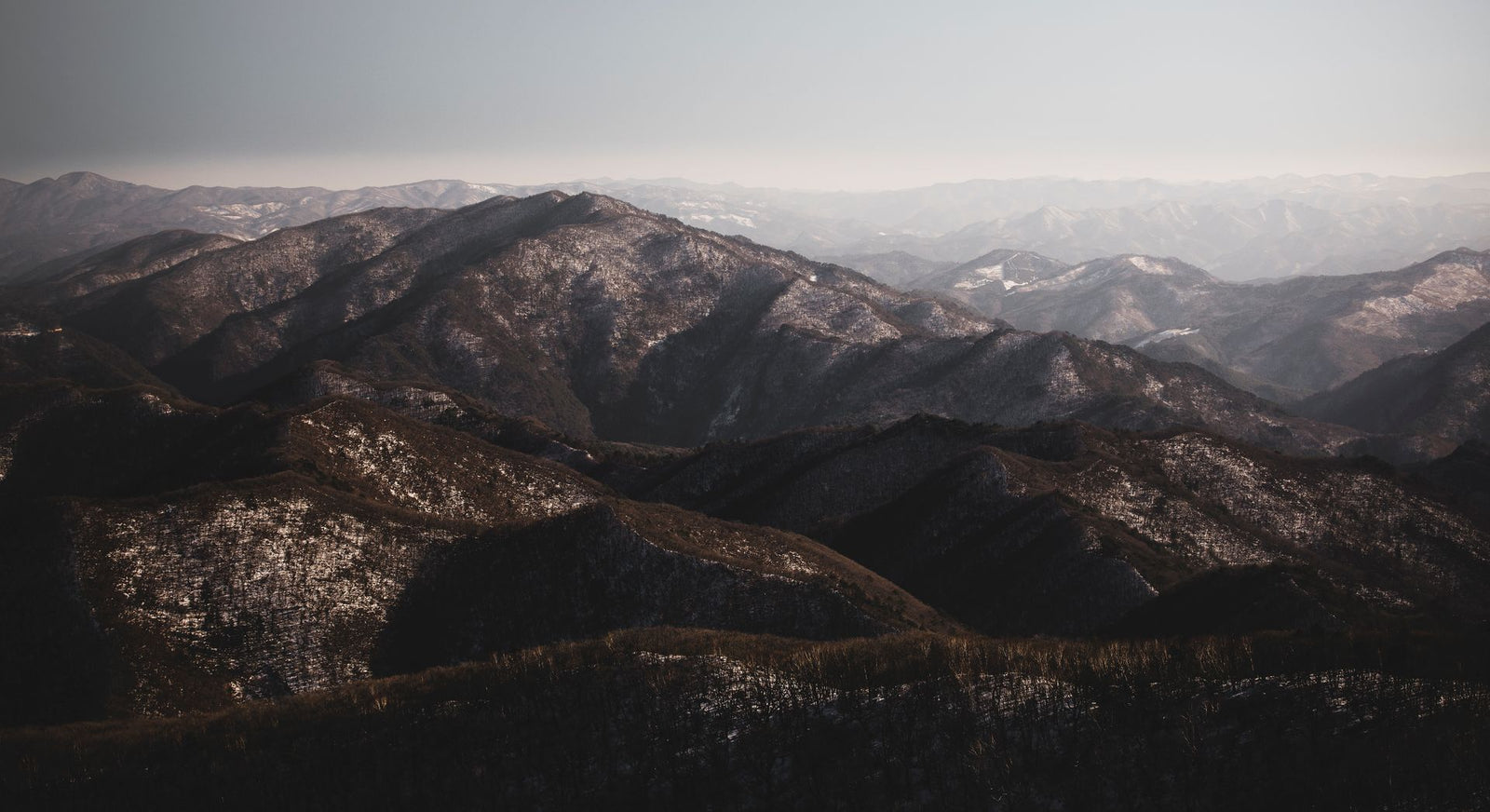Breathtaking aerial view of Pyeongchang's snow-capped mountains under a clear sky.