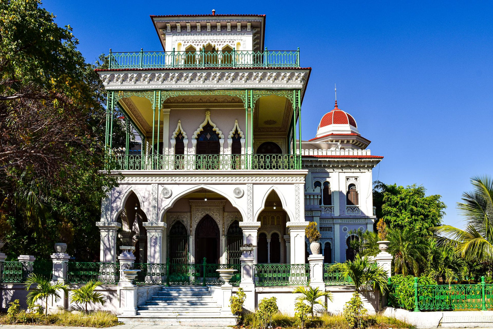 A stunning Moroccan-style mansion in Cienfuegos, Cuba, showcasing intricate architecture and lush gardens.