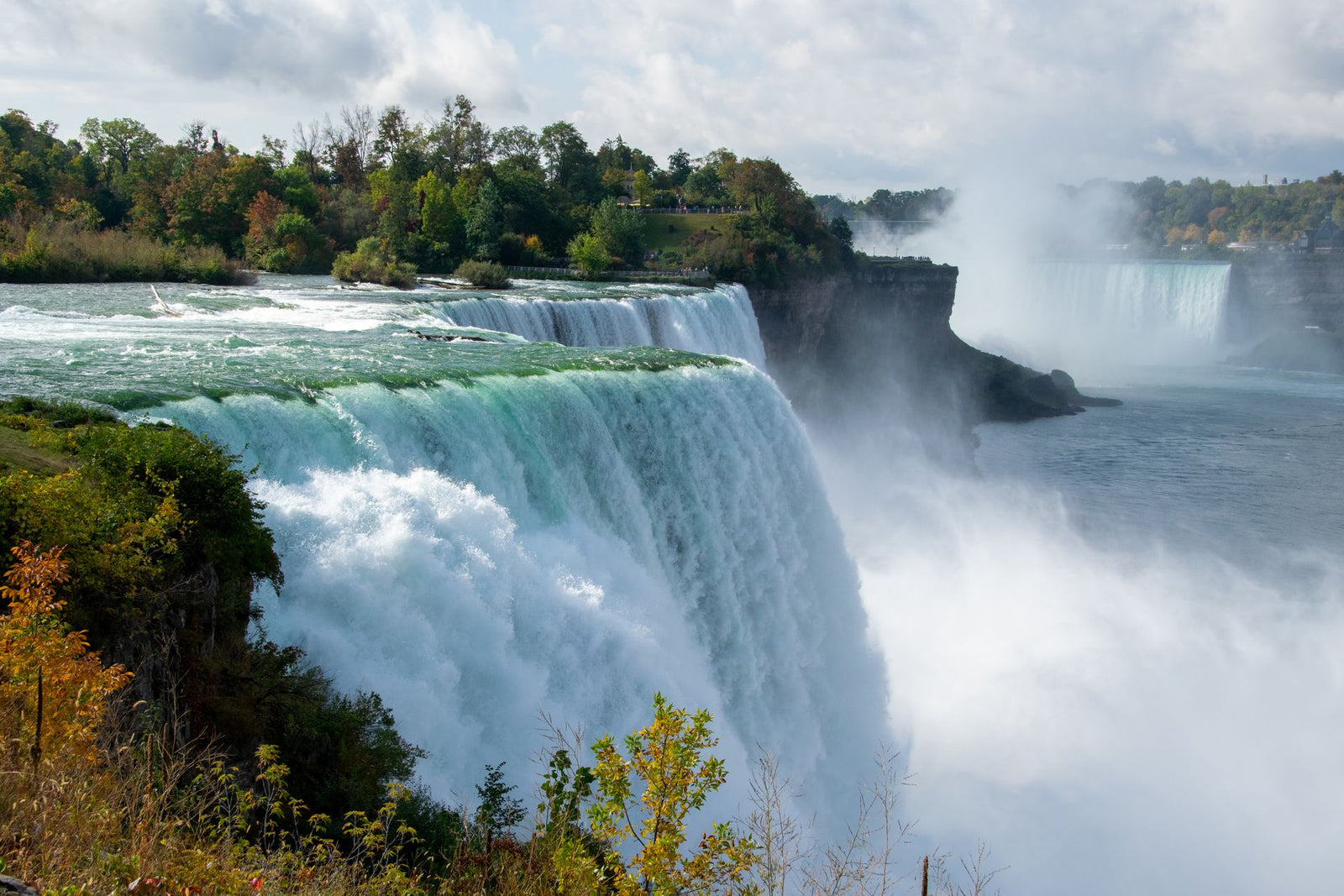 Stunning capture of Niagara Falls with lush autumn foliage and cascading waters.