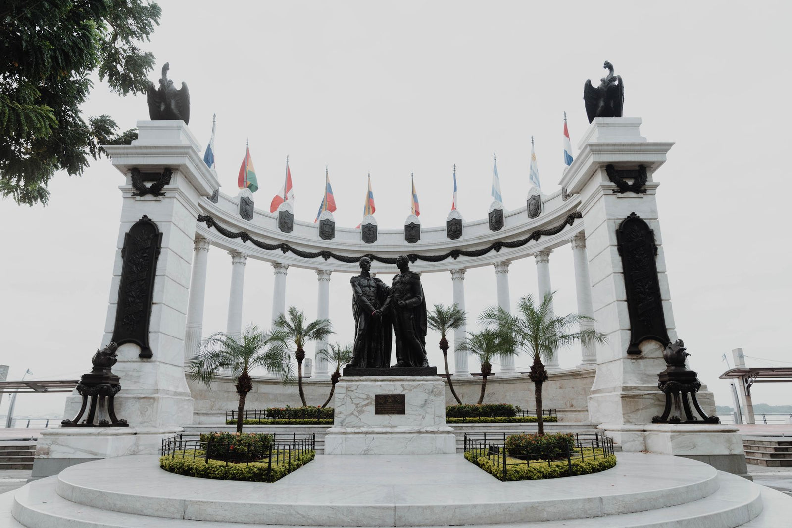 A historic monument featuring statues and flags in Guayaquil, Ecuador symbolizing independence and unity.