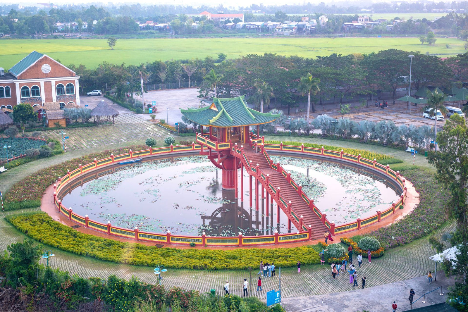 Aerial view of a Vietnamese pagoda surrounded by a pond and green landscape.