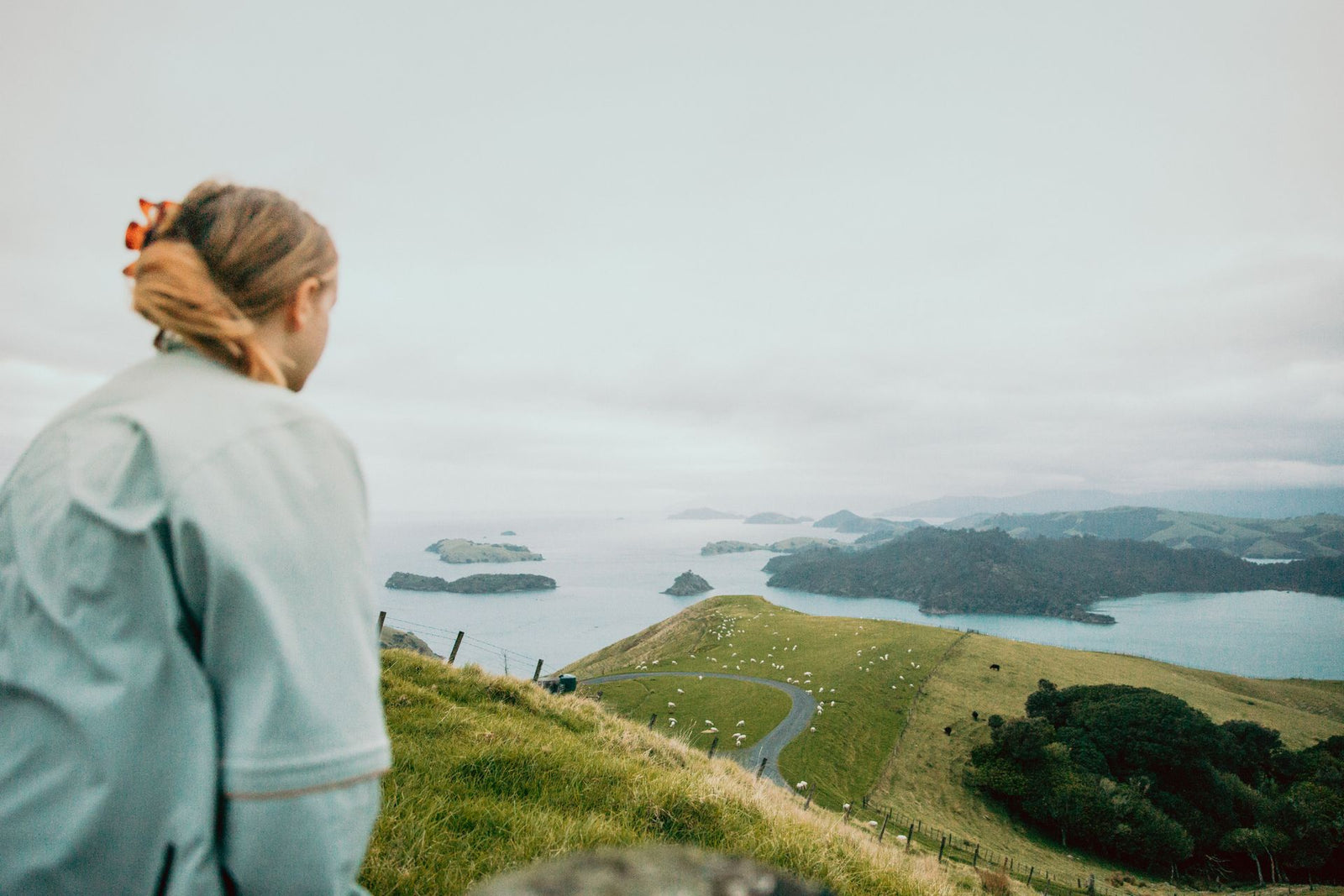 A woman gazes over the picturesque greenery and ocean of Coromandel, New Zealand.