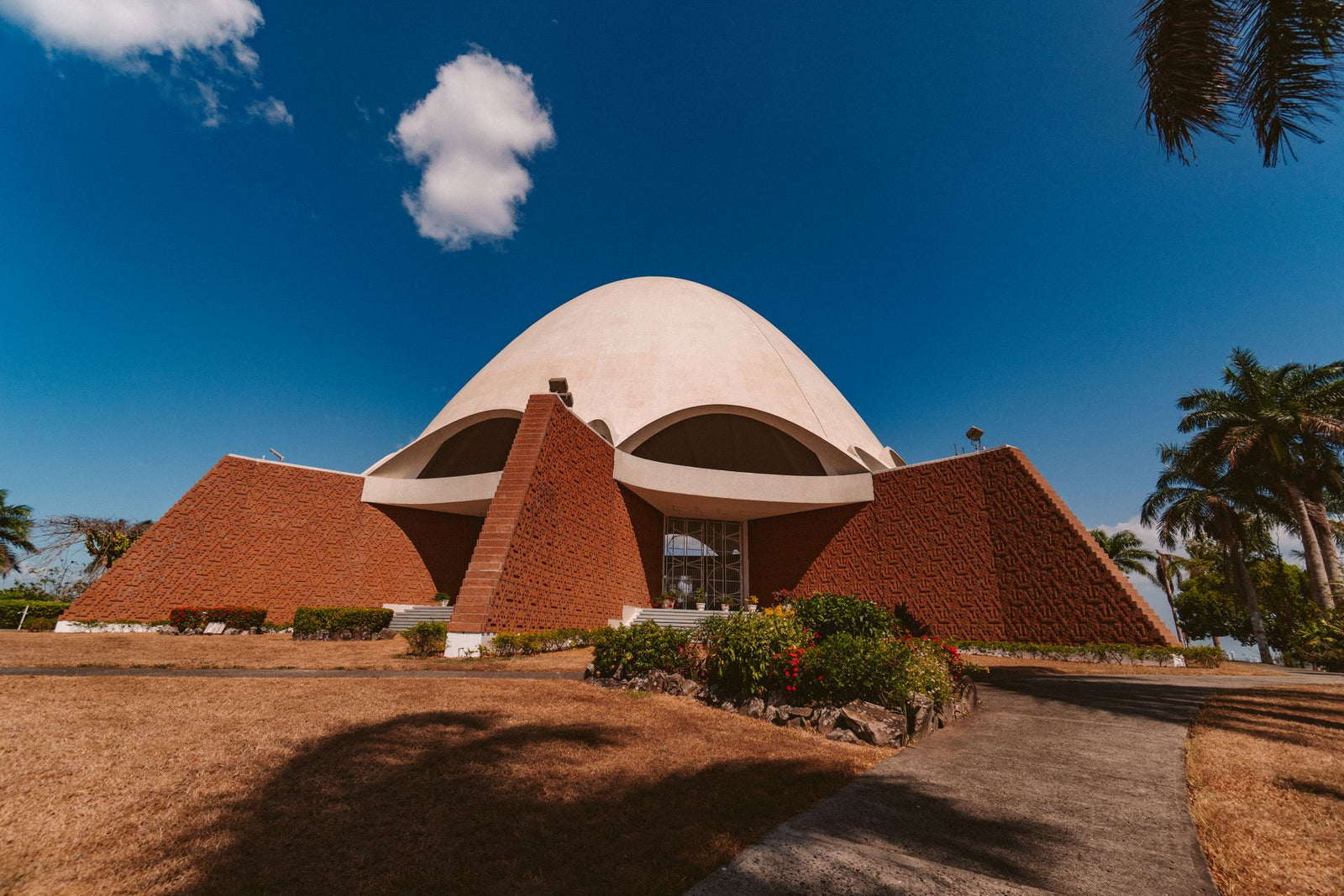 A modern architectural building with a dome and brick facade under a clear blue sky.