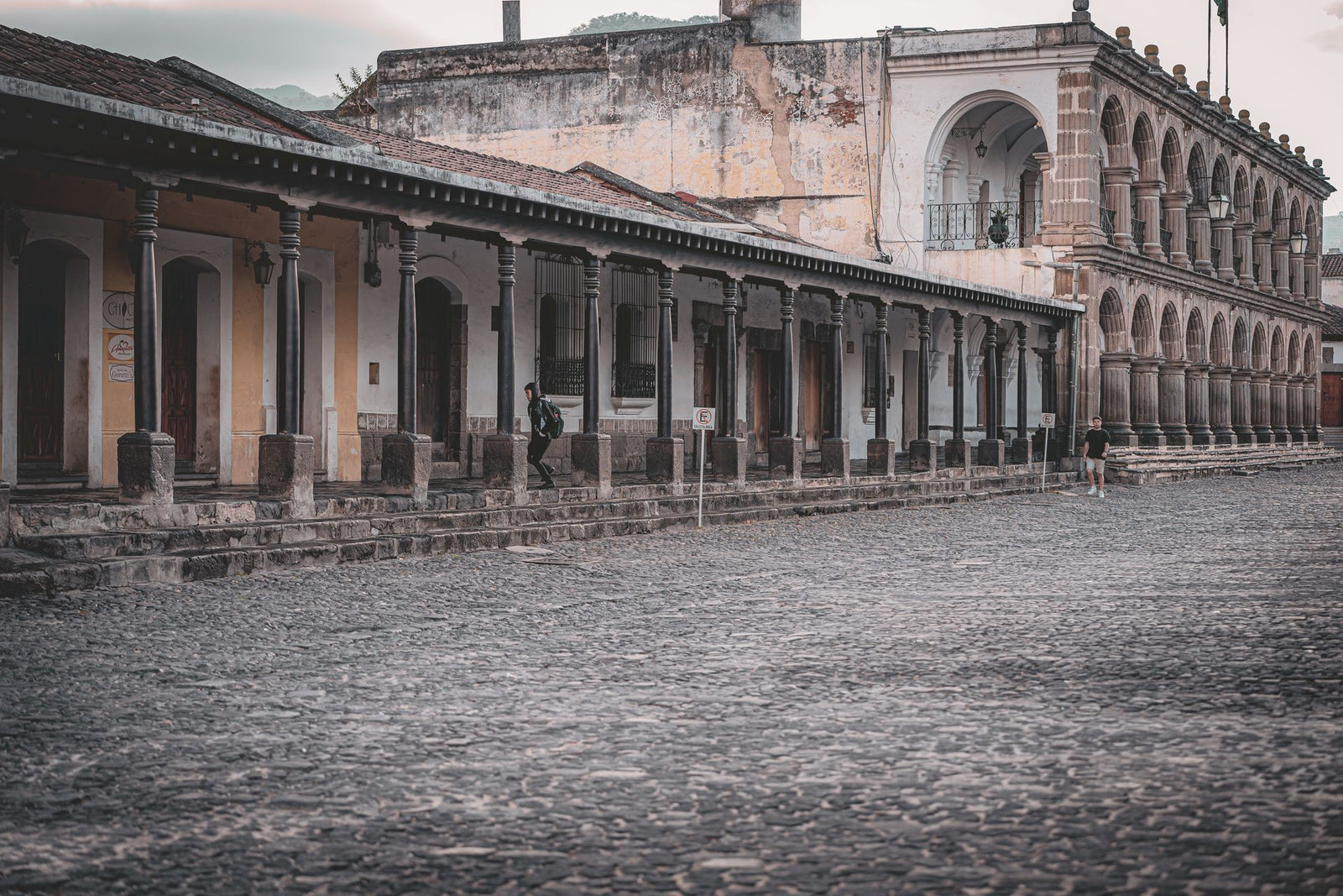 Elegant colonial buildings with stone archways and cobblestone streets in Antigua Guatemala.