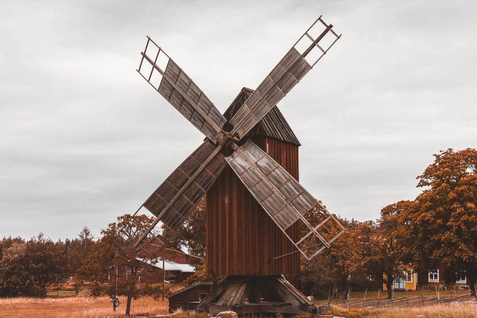 Charming view of a vintage wooden windmill surrounded by autumn foliage in Åland Islands countryside.