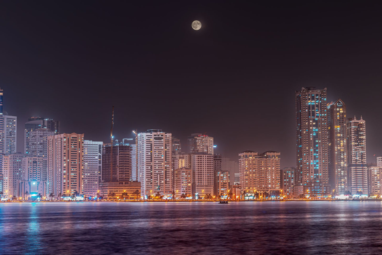 Sharjah skyline at night with full moon — United Arab Emirates