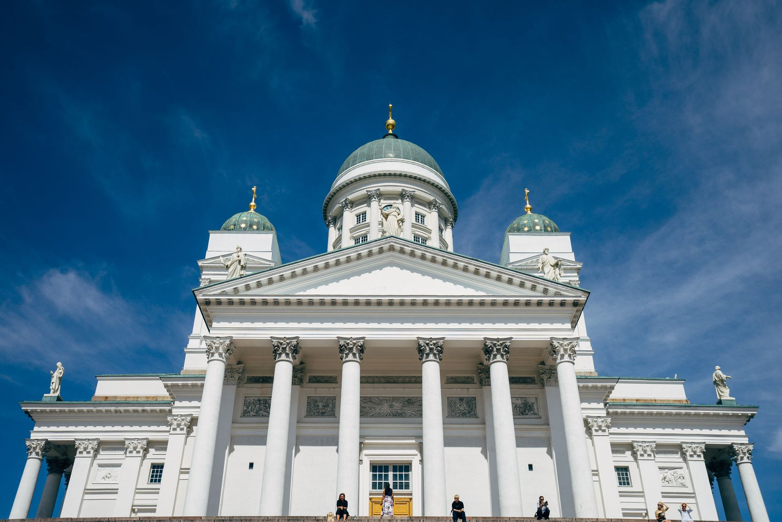 Front view of Helsinki Cathedral against a bright blue sky, highlighting neoclassical architecture.