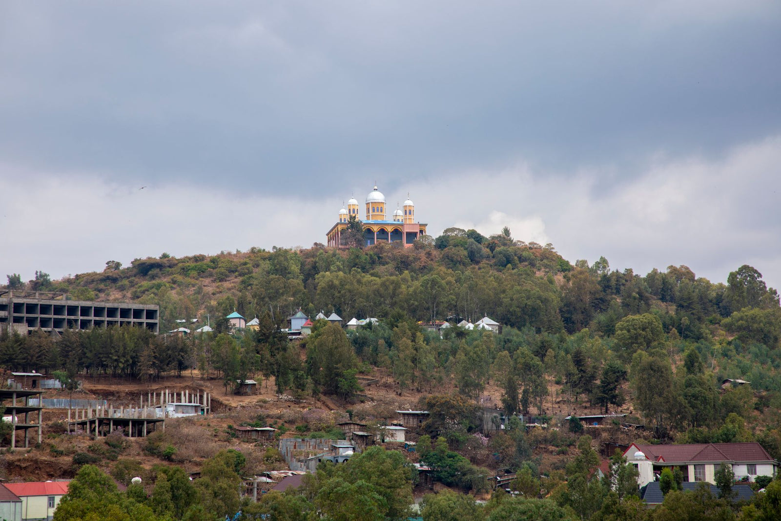 A captivating view of Gondar, Ethiopia showcasing iconic architecture atop a verdant hillside under a cloudy sky.