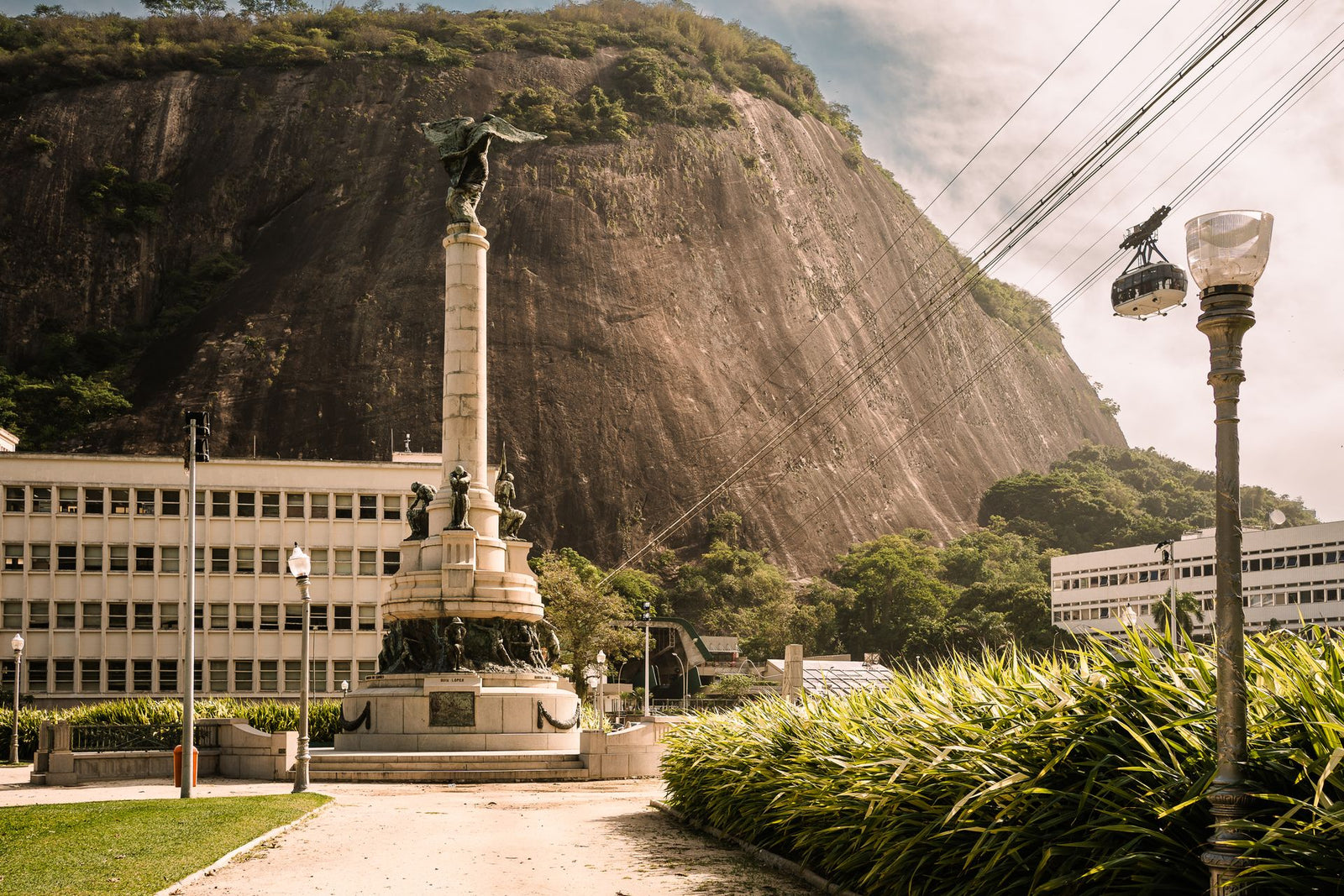 A statue with cable cars and mountain backdrop in Rio de Janeiro, Brazil.