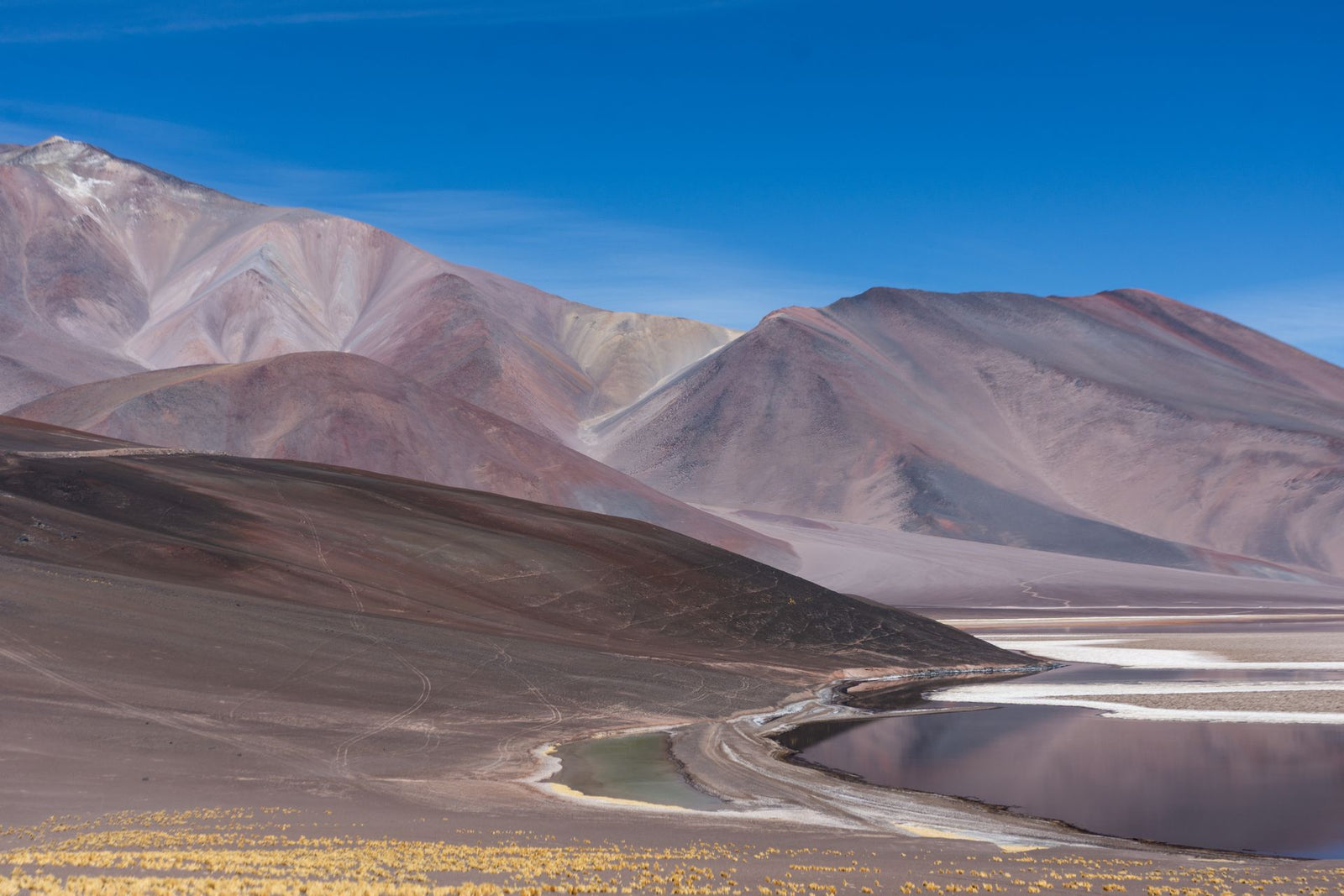 Breathtaking view of colorful Andes mountains near a serene lake in Catamarca, Argentina.