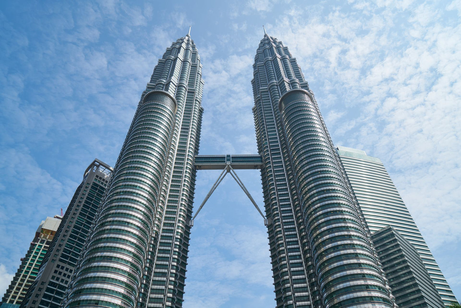 The iconic Petronas Twin Towers against a bright blue sky in Kuala Lumpur, Malaysia.