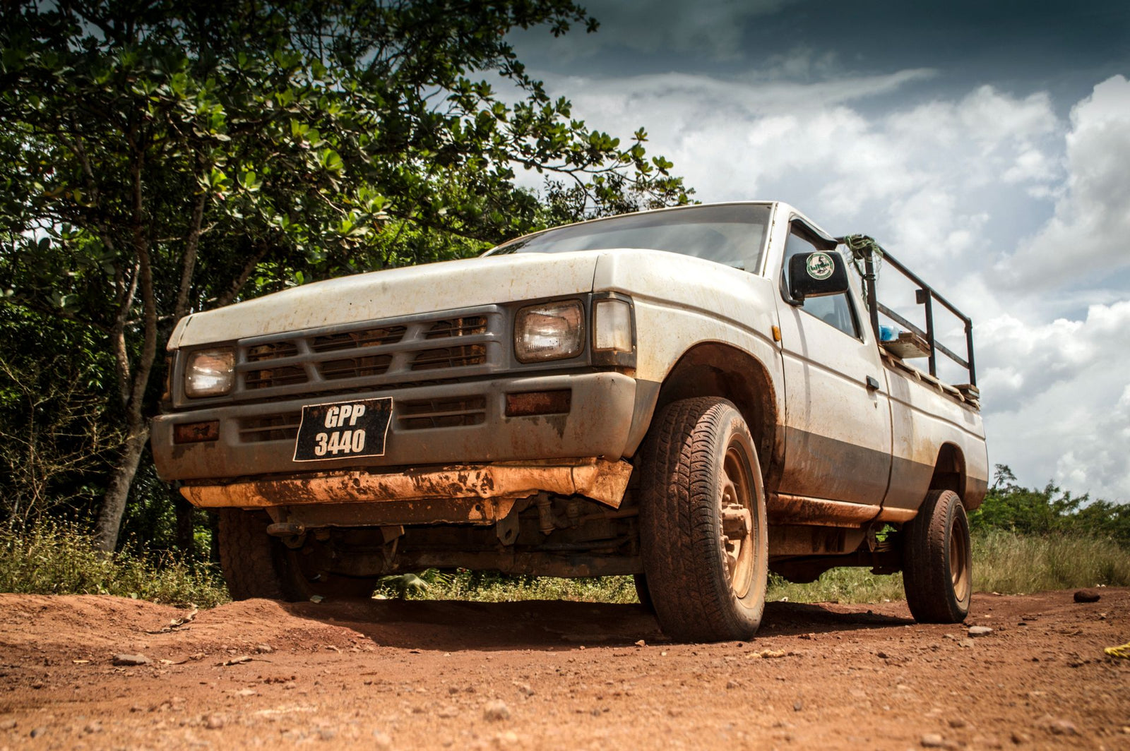 Low-angle shot of a vintage pickup truck navigating a dirt road in the Guyana wilderness.