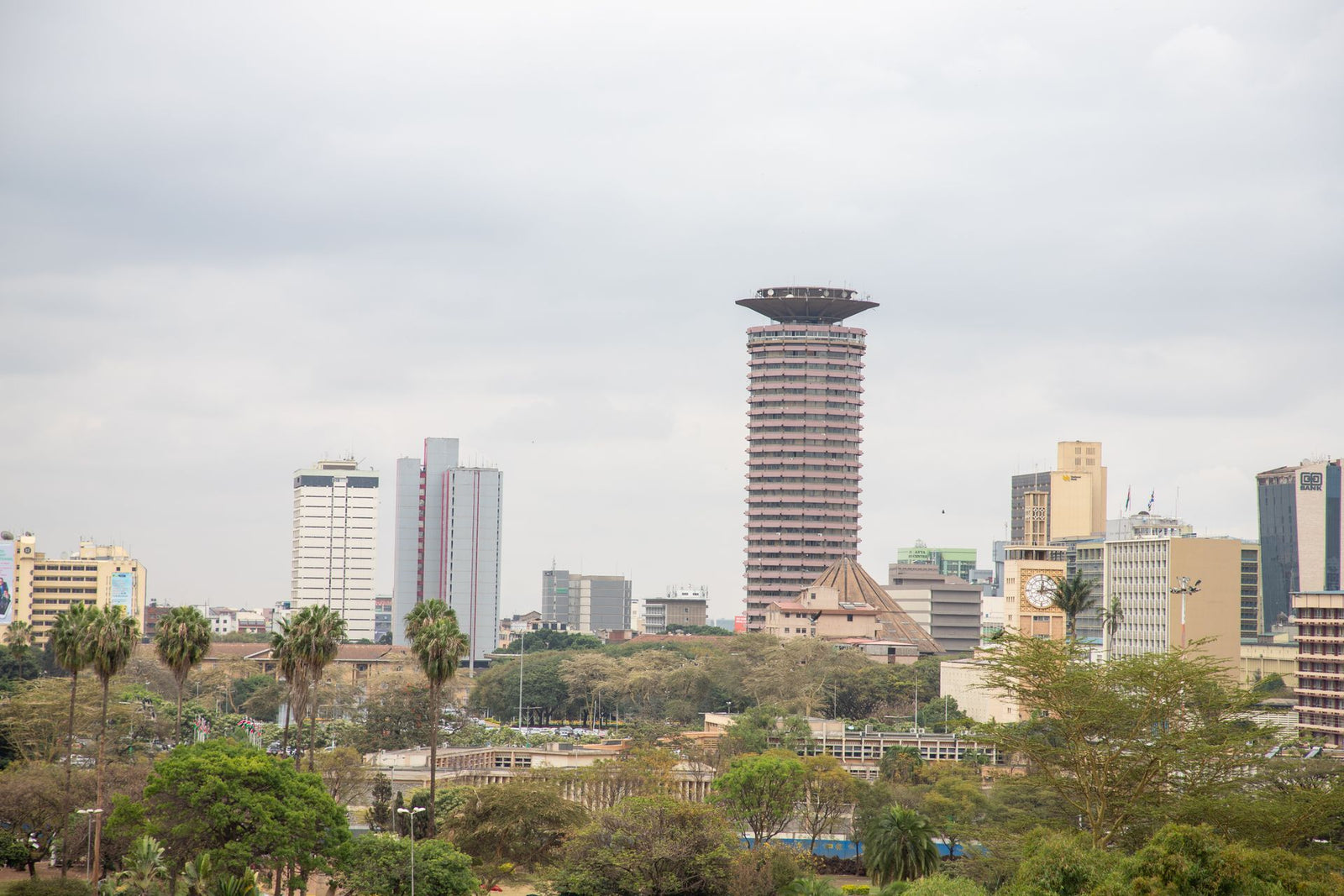 View of Nairobi's skyline with the iconic KICC tower and surrounding high rises under a cloudy sky.